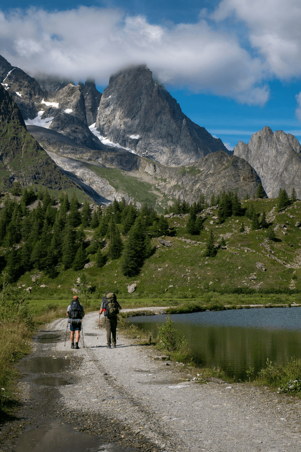 Couple walking along side a lake overlooking mountains and low cloud
