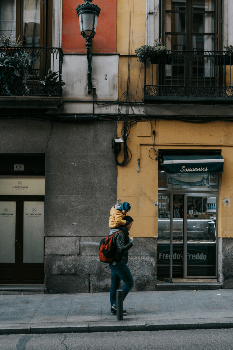 Father walking up the street with toddler on his shoulders