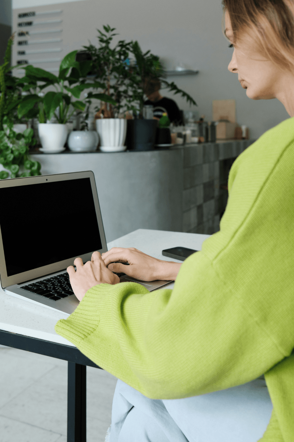 Girl wearing lime green jumper typing on MacBook