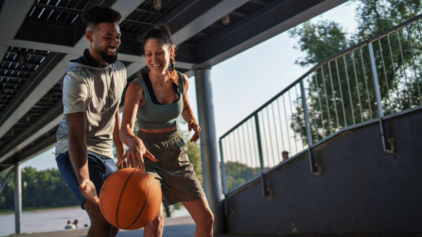 Smiling couple playing basketball