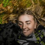 Smiling girl lying on the grass with her dog