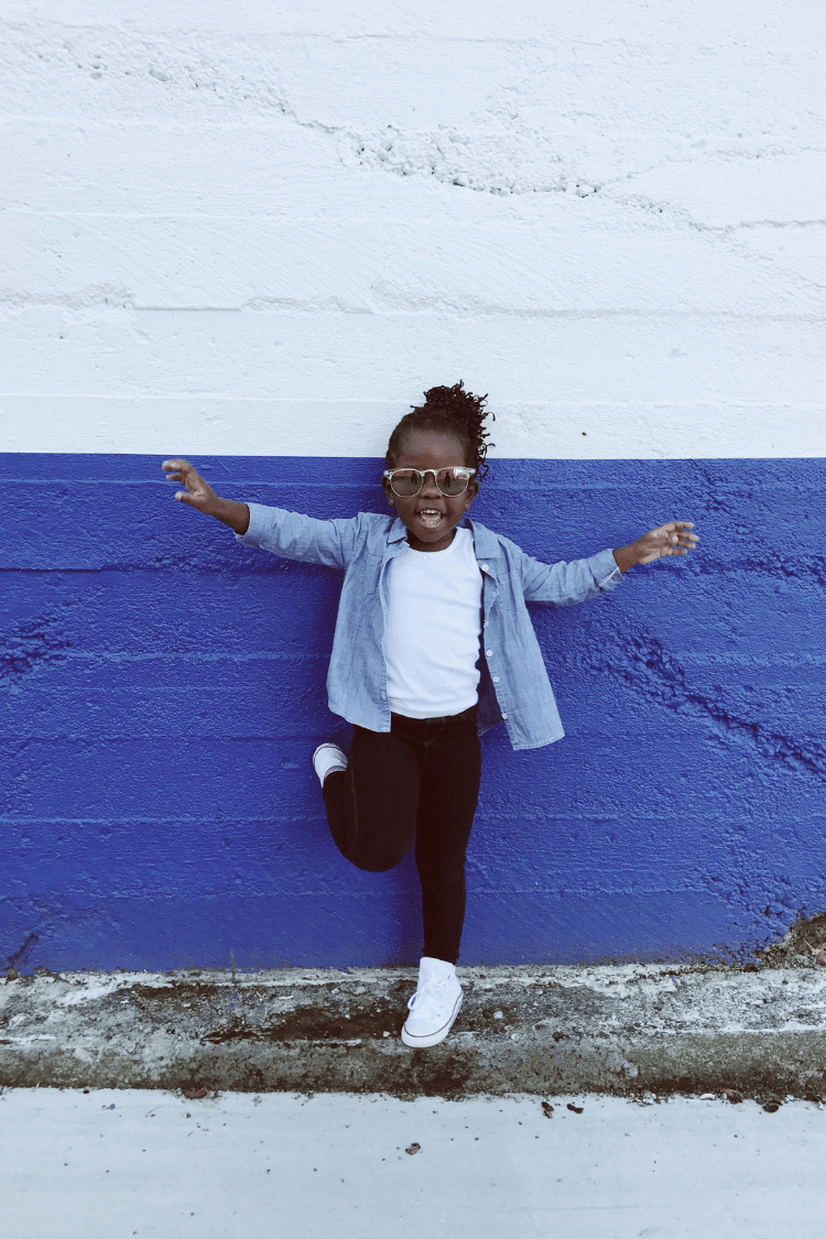 Smiling young girl standing against a blue wall
