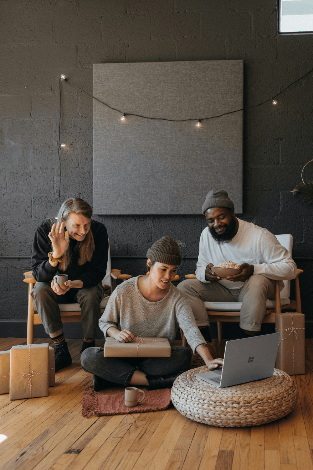 Three young people gathered around a computer screen smiling
