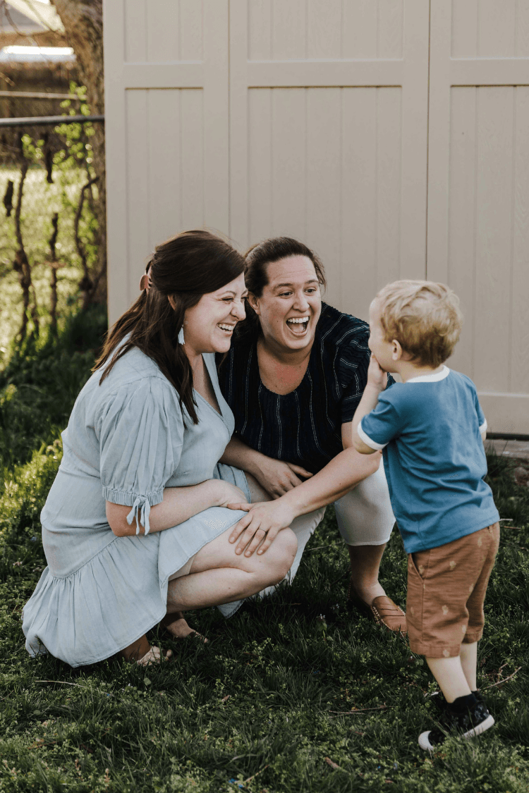 Two mums laughing with their toddler son