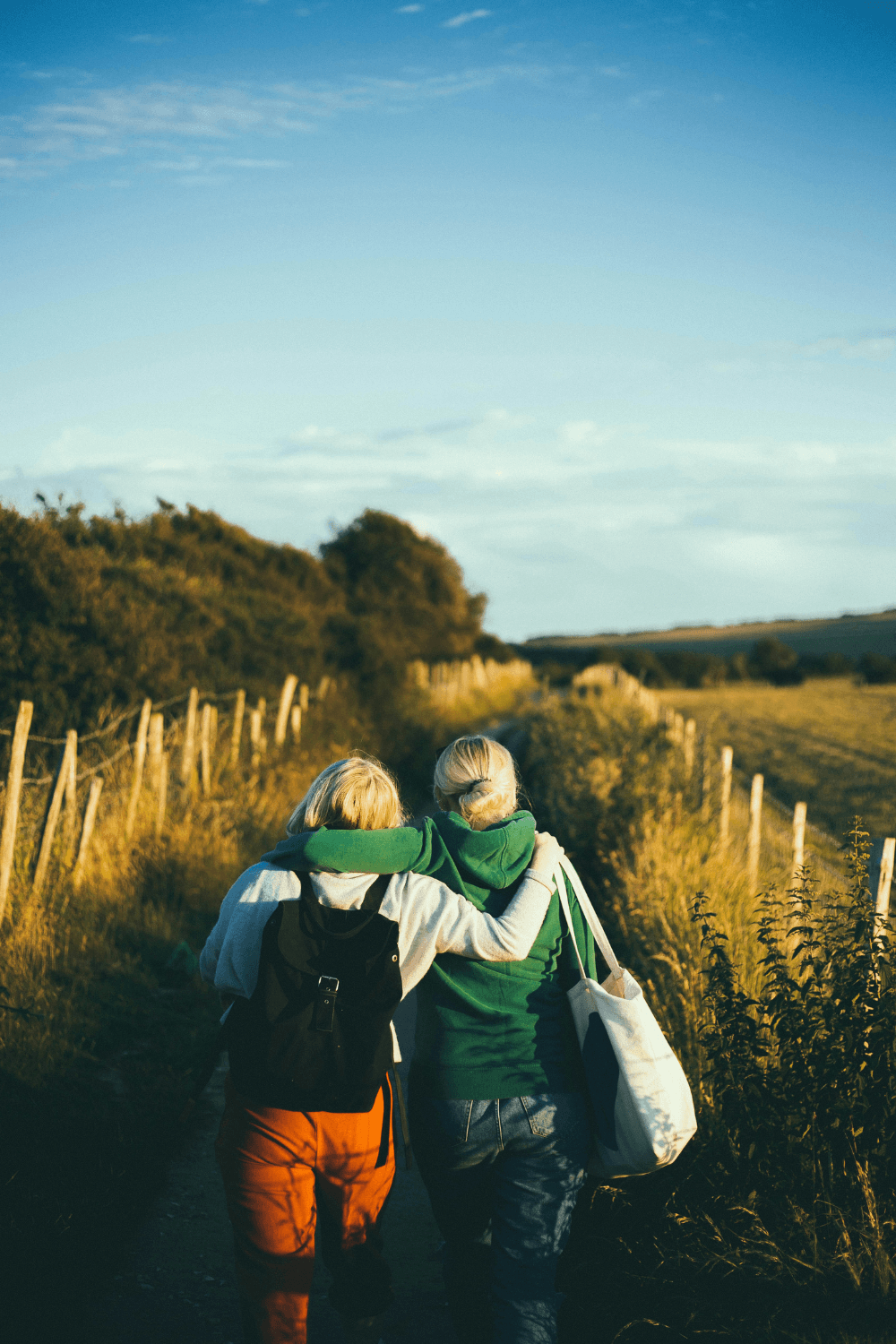 Two women walking together along the edge of a field