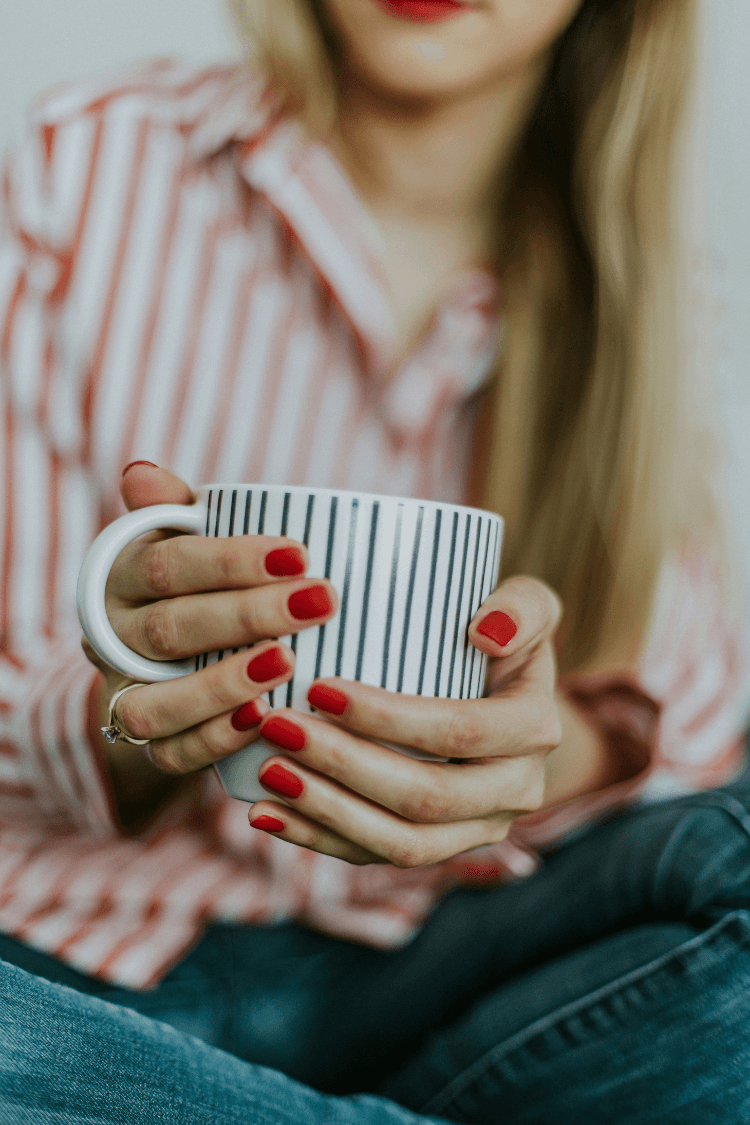Woman holding a white coffee mug with navy stripes