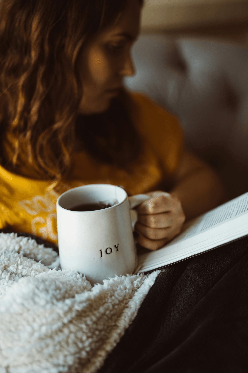 Woman holding white mug with joy written on