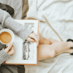 Woman reading book and holding mug of coffee