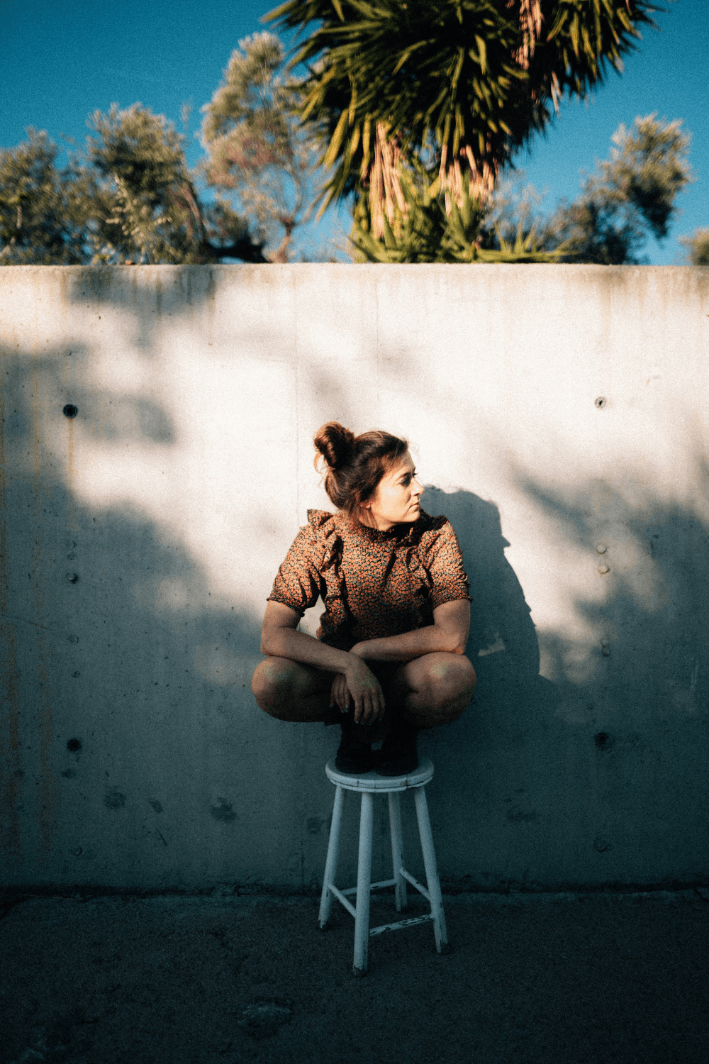 Woman sitting on a stool in front of a wall