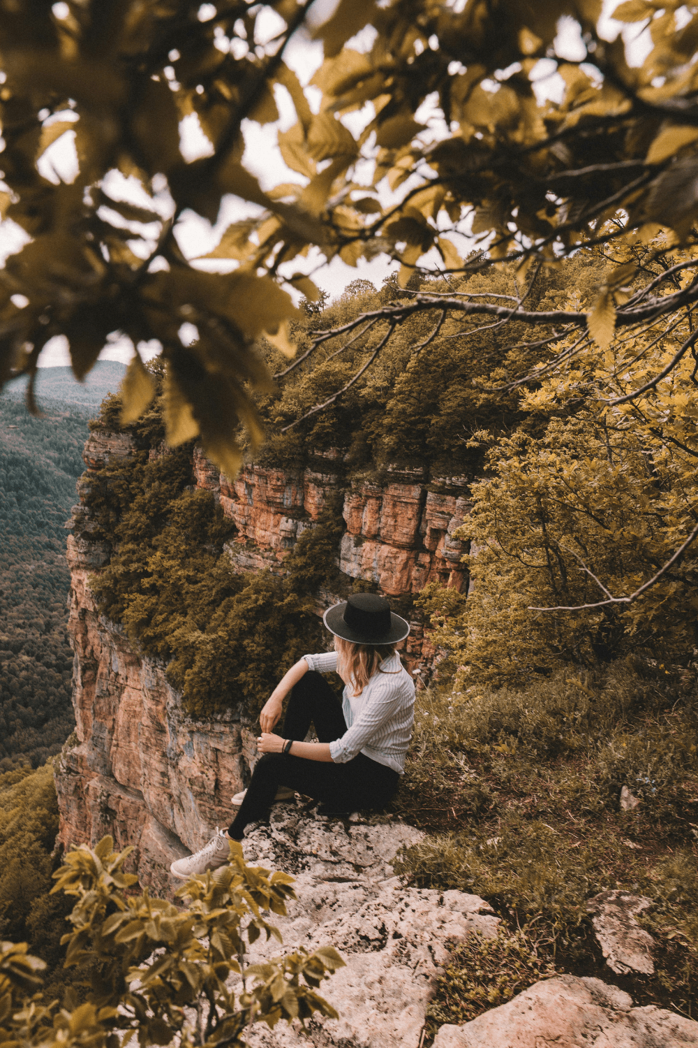 Woman sitting on mountain top looking at surroundings