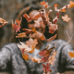 Woman throwing autumn leaves into the air