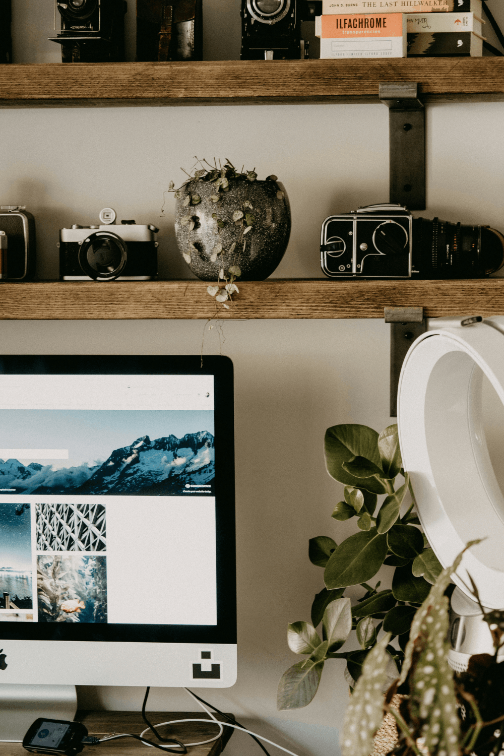 Workspace with iMac and shelves with old cameras on