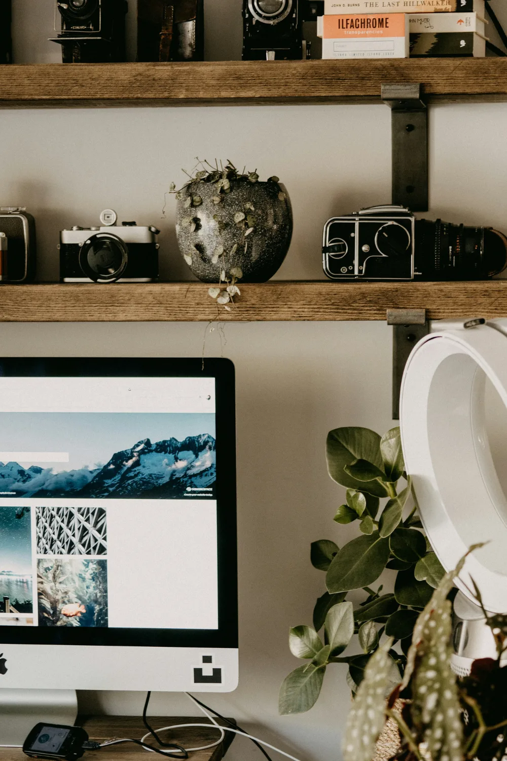 Workspace with iMac and shelves with old cameras on