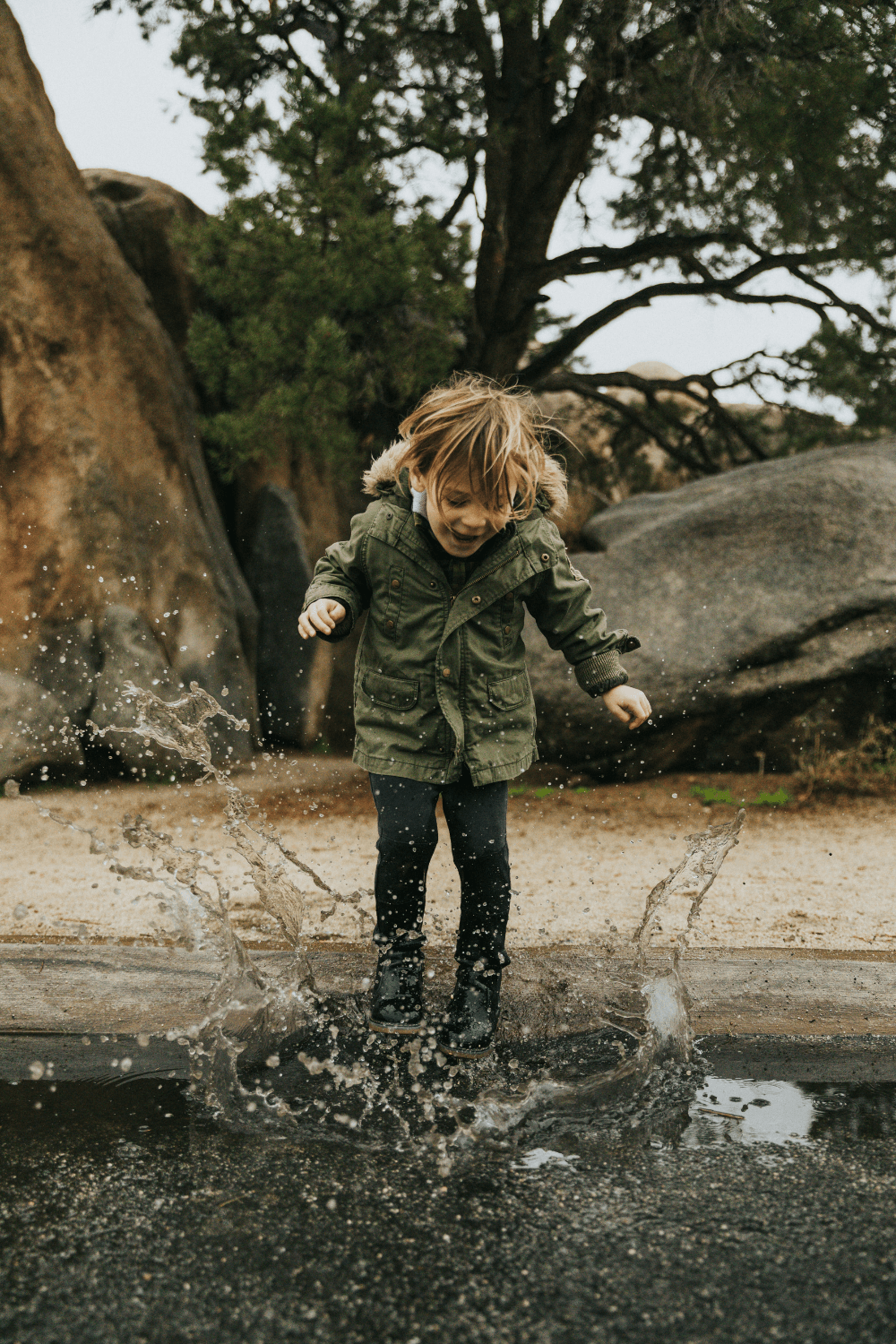 Young boy jumping in puddle on cold day