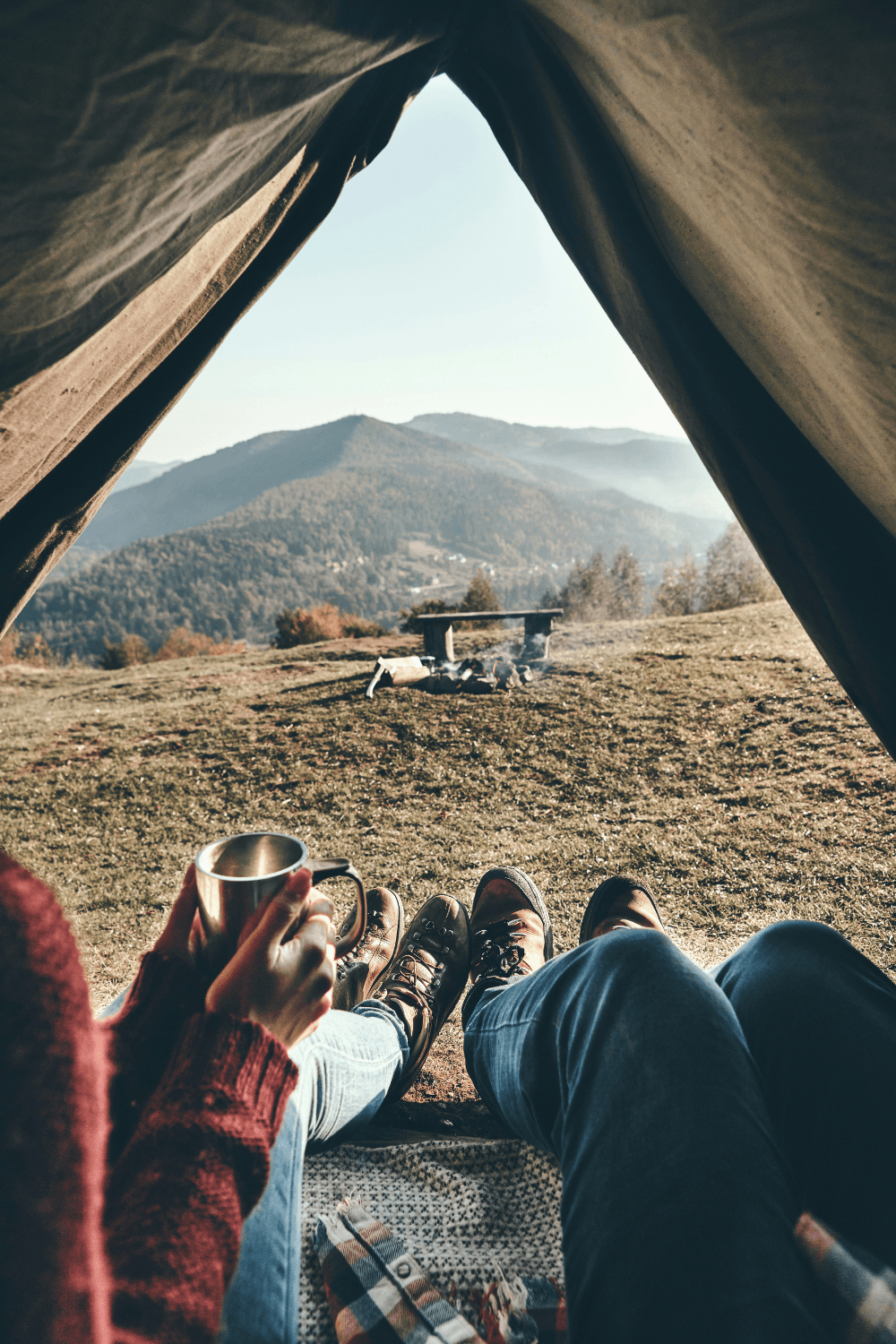 Young couple having coffee in their ten overlooking a mountain range