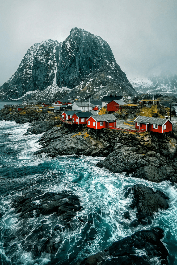 A town in Lofoten, Norway which red wooden houses and mountain in the background