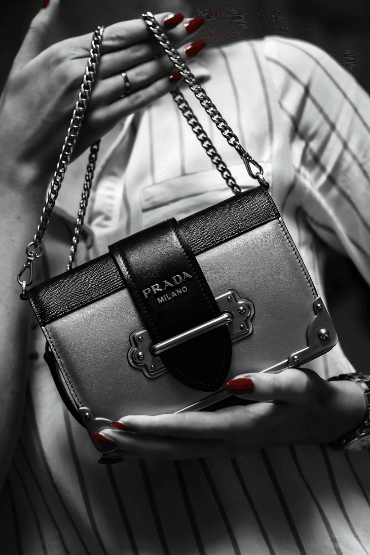 Black and white photo of woman holding Prada bag