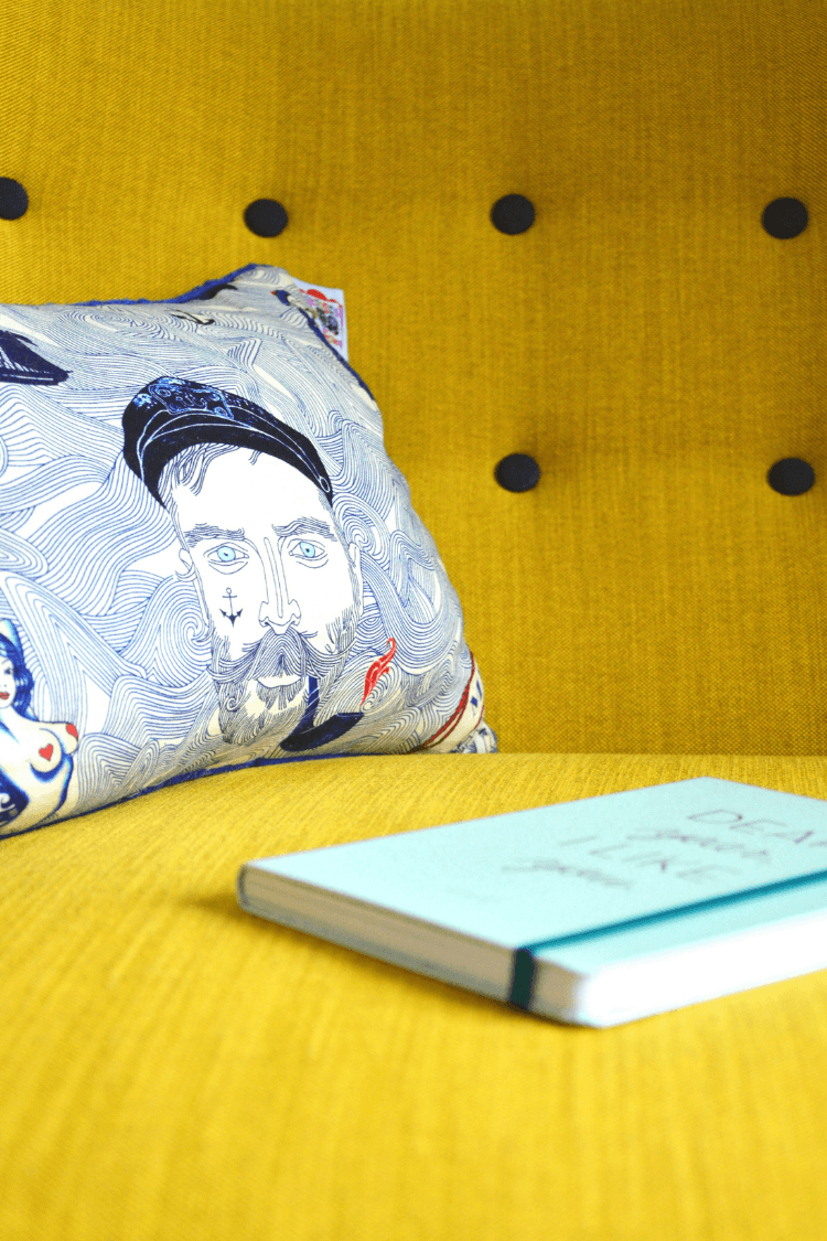 Blue notebook on yellow sofa with cushion