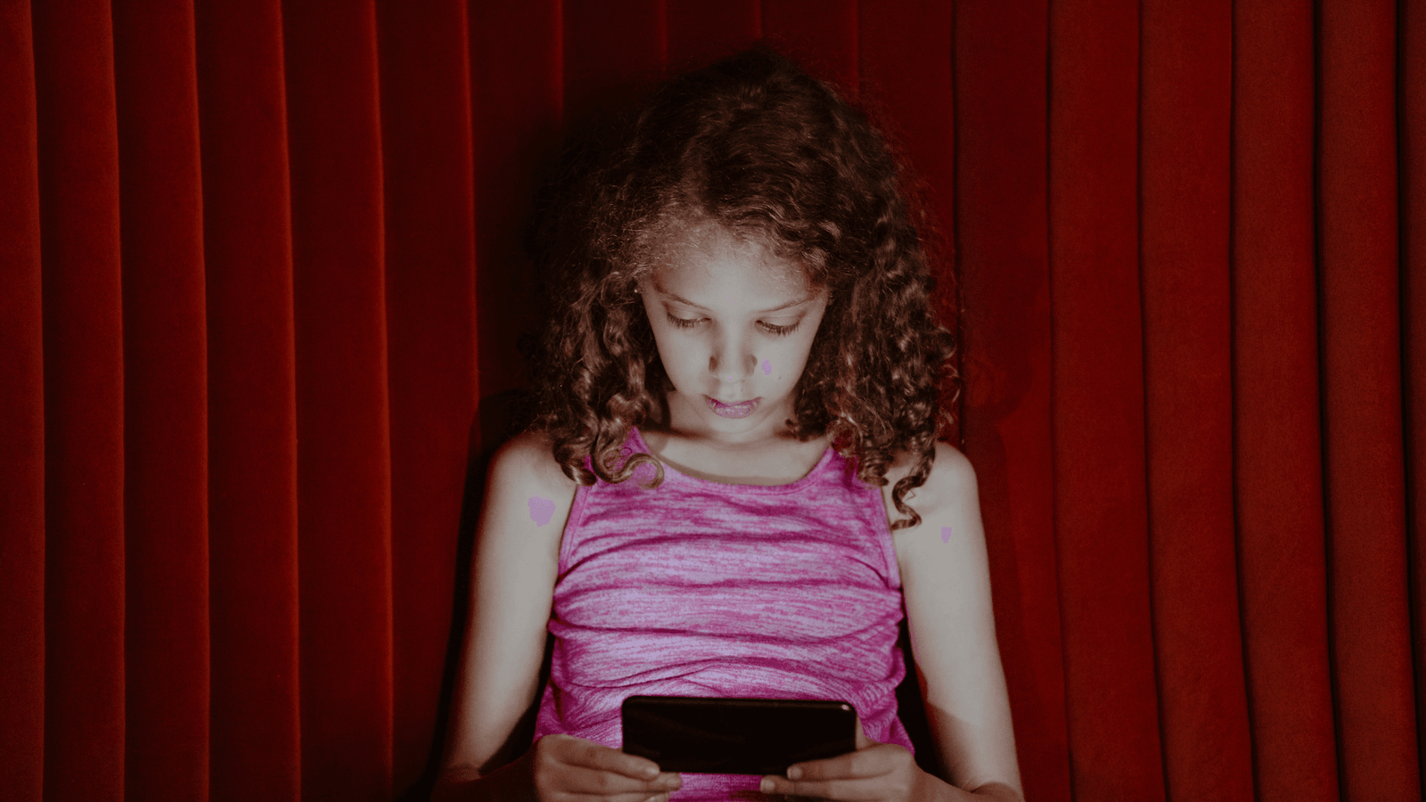Child looking at smartphone against a red background