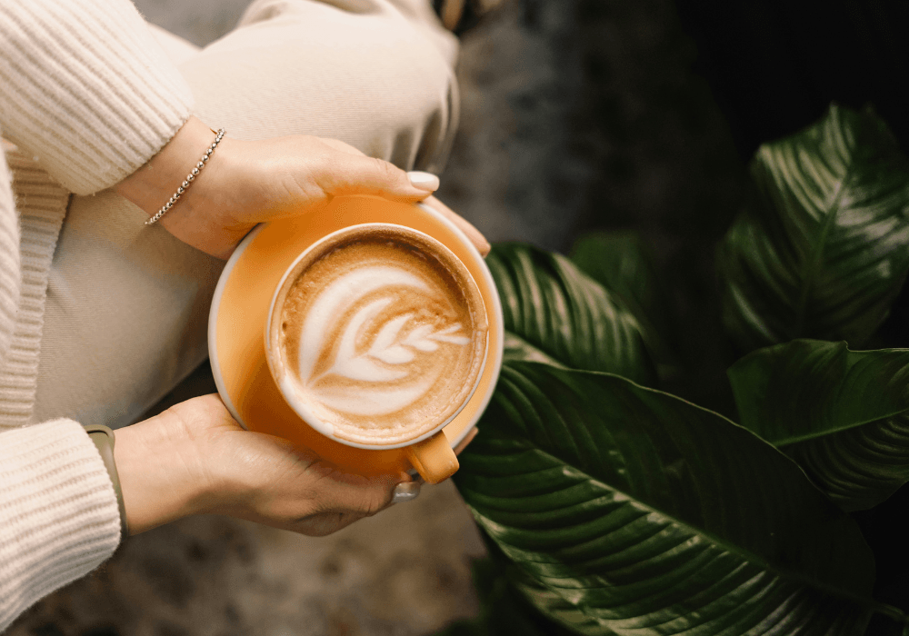 Close-up of woman in cream jumper holding cup of coffee