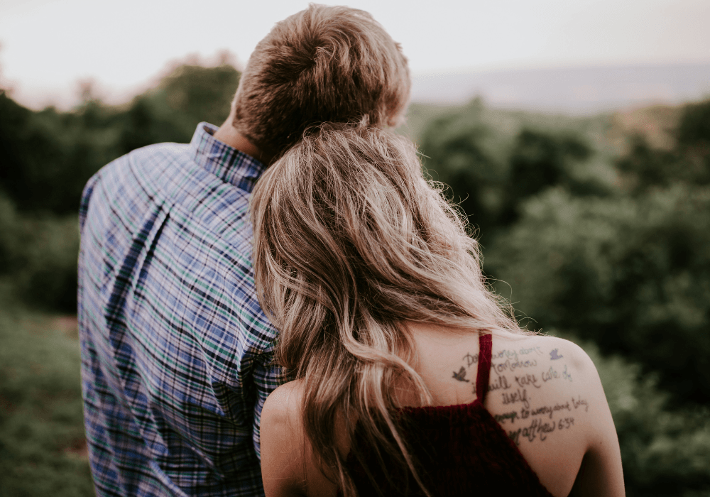 Couple standing with their backs to the camera supporting each other