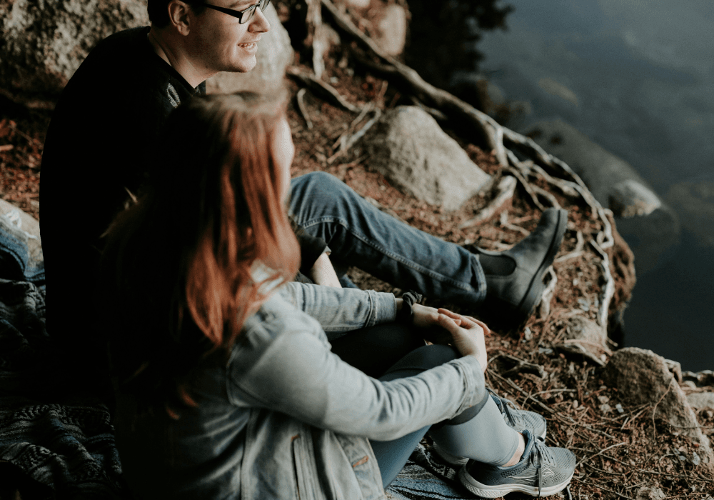 Couple talking together on rocks overlooking the sea