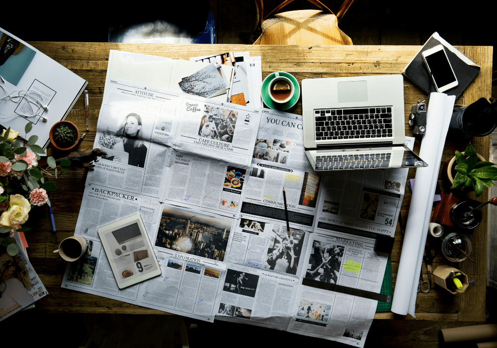 Desk with laptop, iPad, mug and newspaper