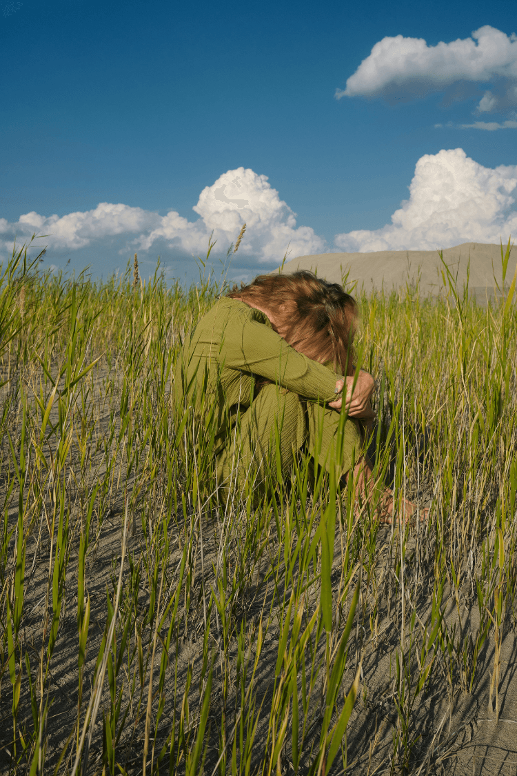 Girl in a green dress sitting on grass