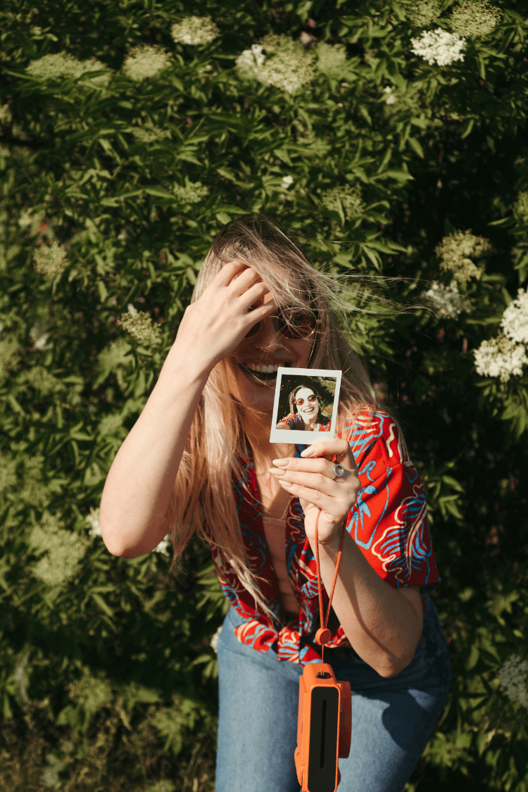Girl laughing at photo from poloroid camera