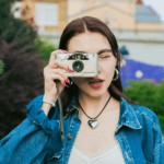 Girl wearing denim jacket looking through camera lens