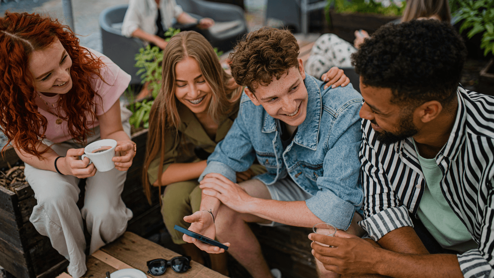 Group of four friends sitting together in outside bar
