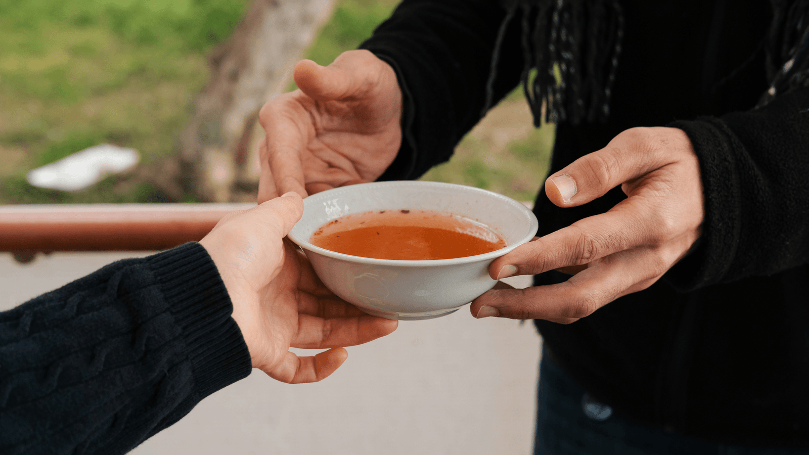 Man offering tomato soup to person in need