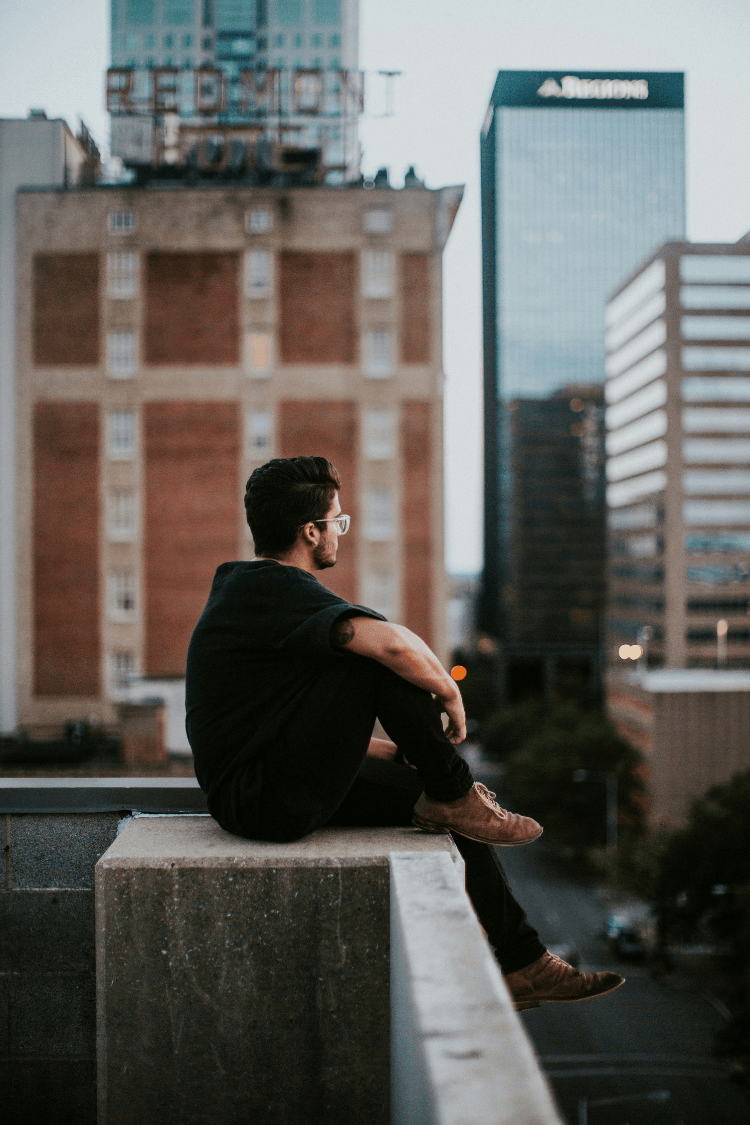 Man sitting alone on wall thinking