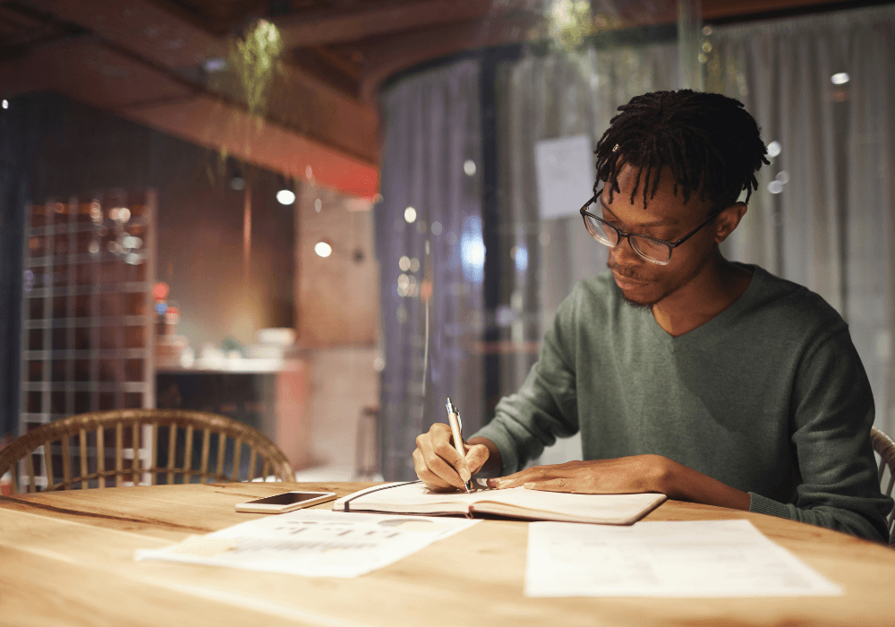 Man sitting at table writing in notebook