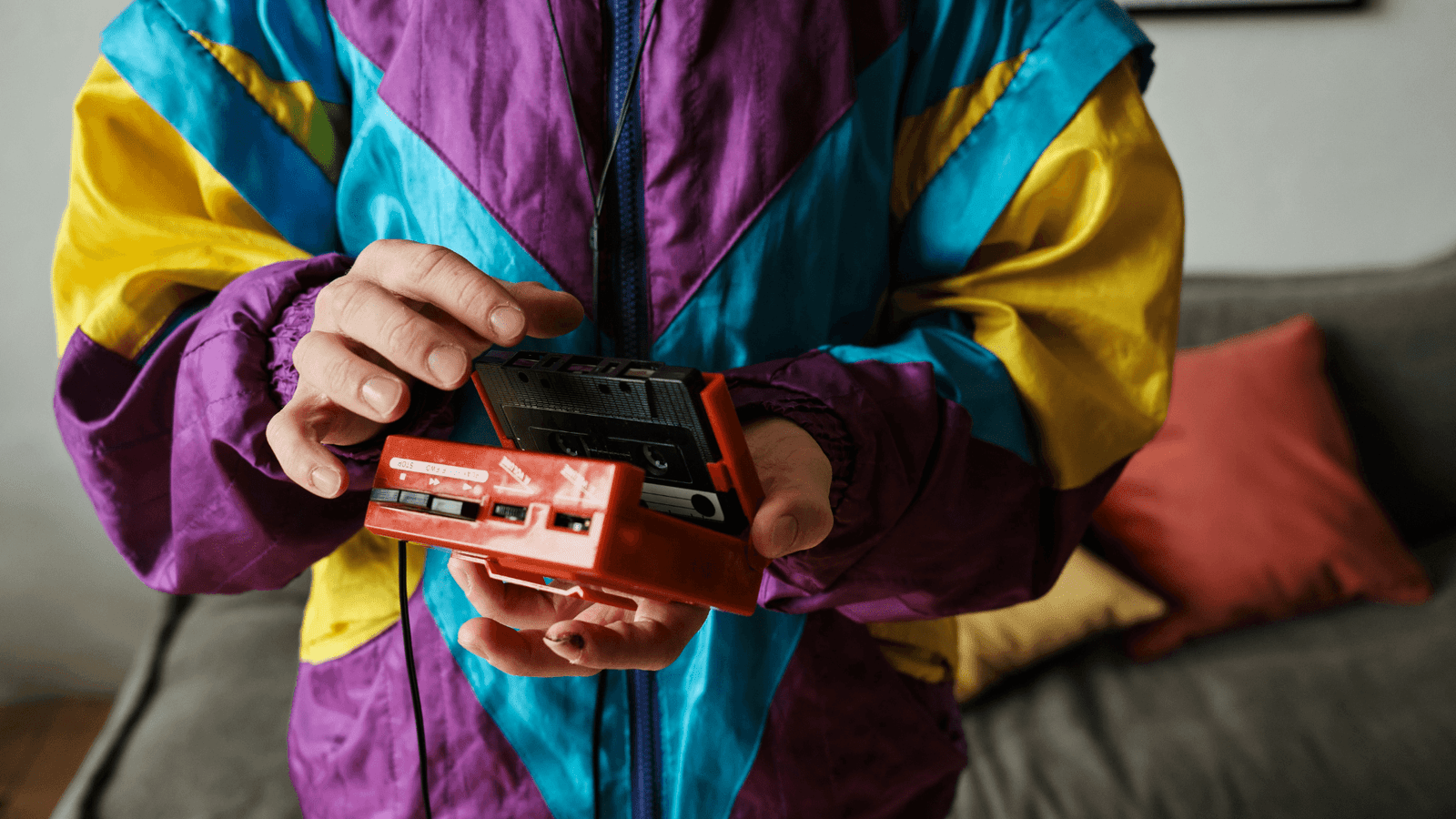 Man wearing a shell suit opening a portable cassette player