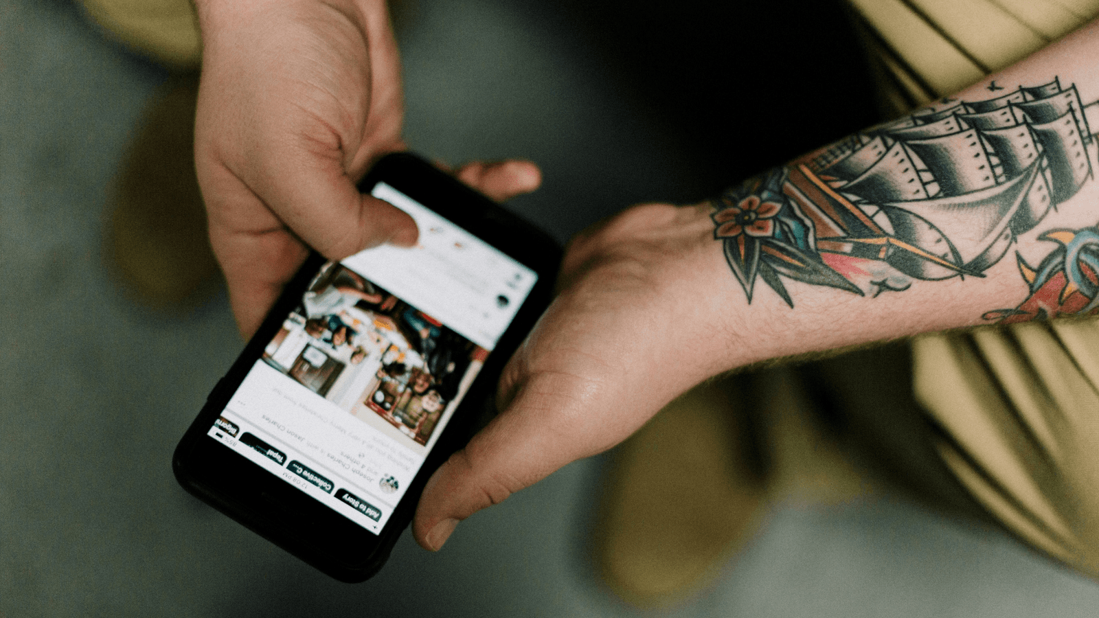 Man with tattooed arm holding smartphone
