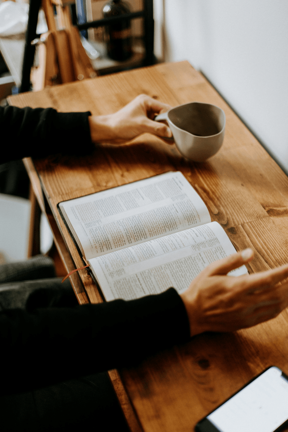 Person studying at desk with mug and open book