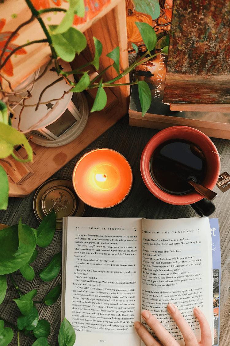 Reading Harry Potter book by candle and cup of tea