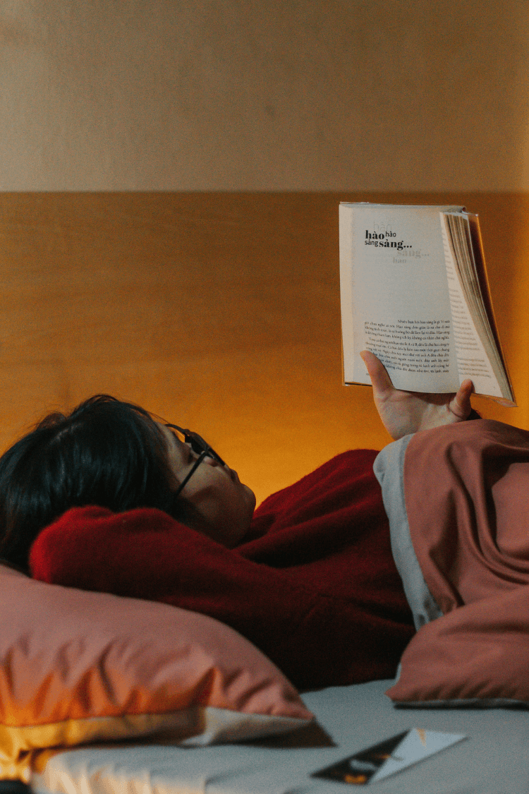 Teenage girl lying down reading a book