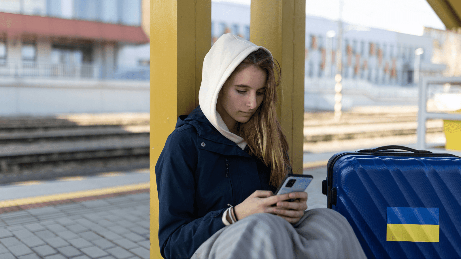 Teenager at train station looking at smartphone