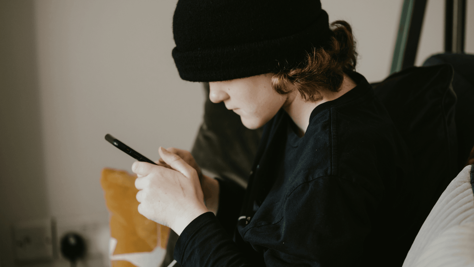 Teenager dressed all in black looking at smartphone