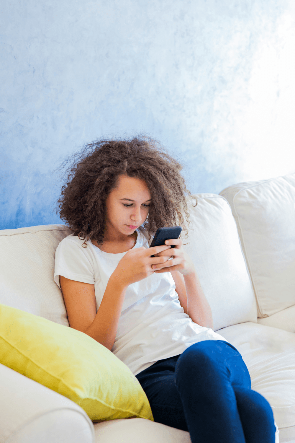 Teenager sitting on sofa looking at phone