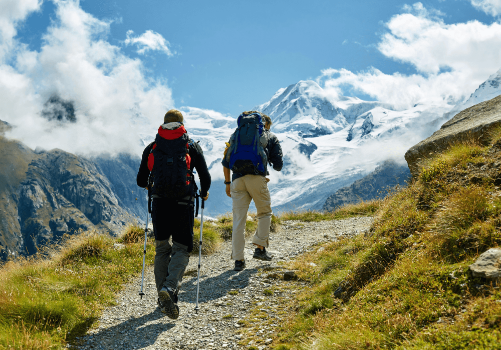Two men hiking with snow topped mountain in the distance