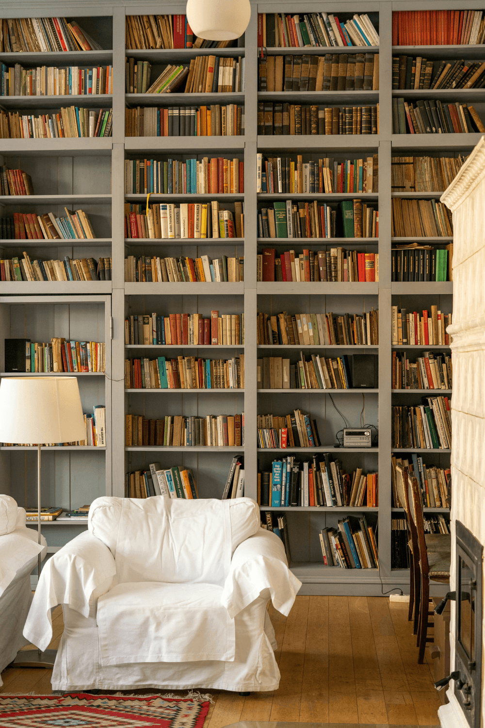 White armchair in front of floor to ceiling bookshelves