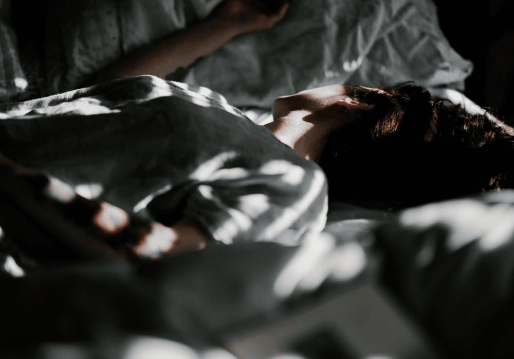 Woman asleep on bed with sun's rays coming in through window