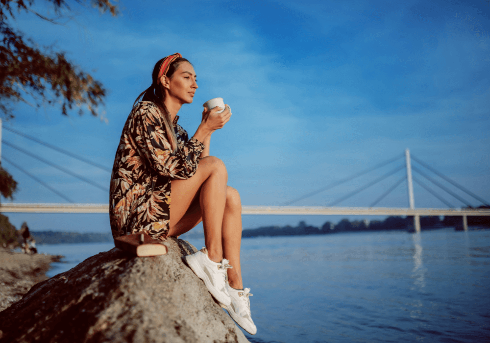 Woman drinking coffee and looking out to sea