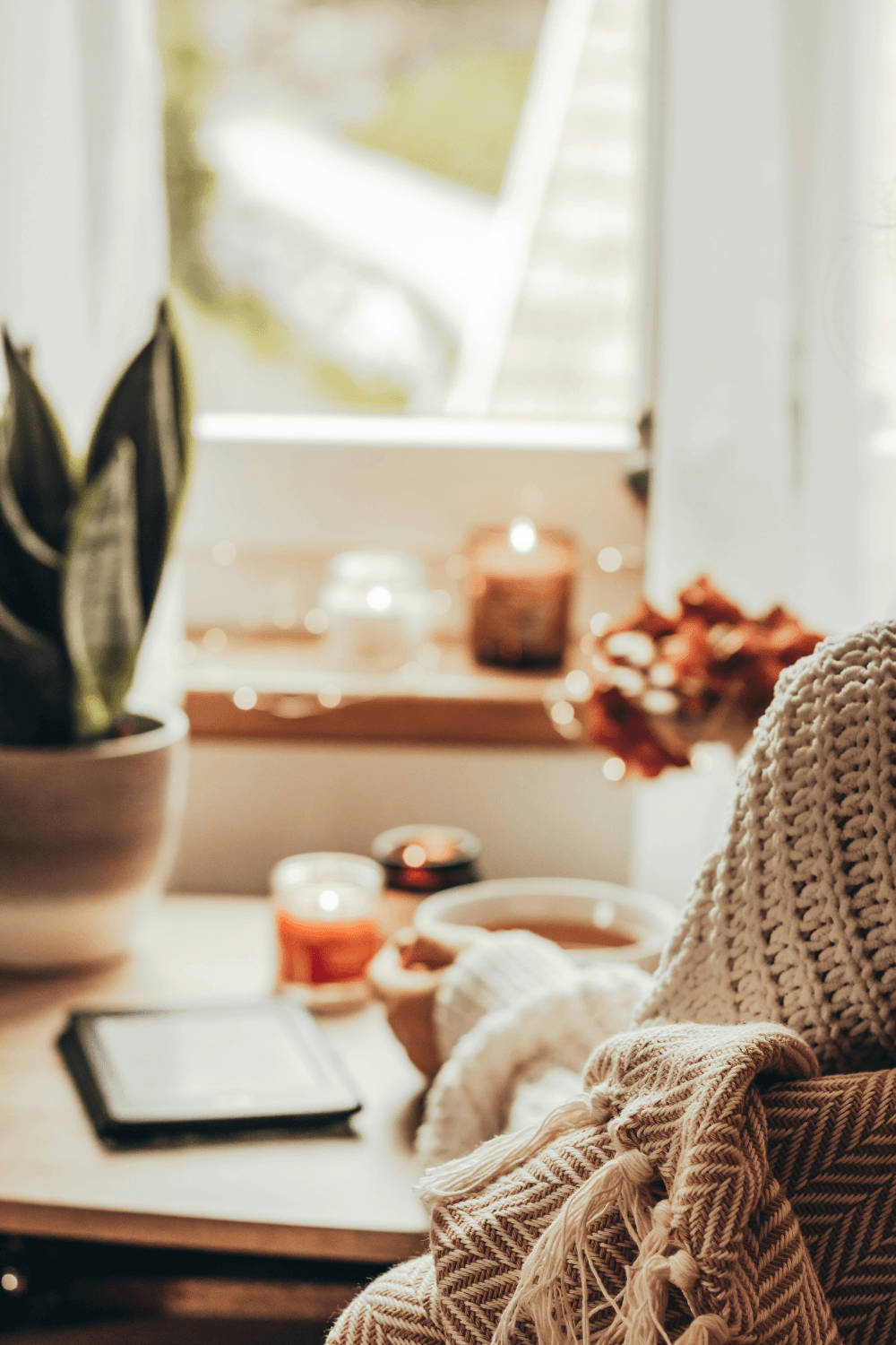Woman holding warm cup of coffee in front of window