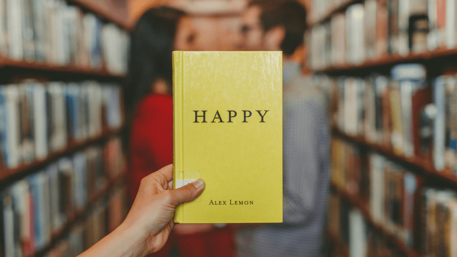 Woman in library holding a book called happy