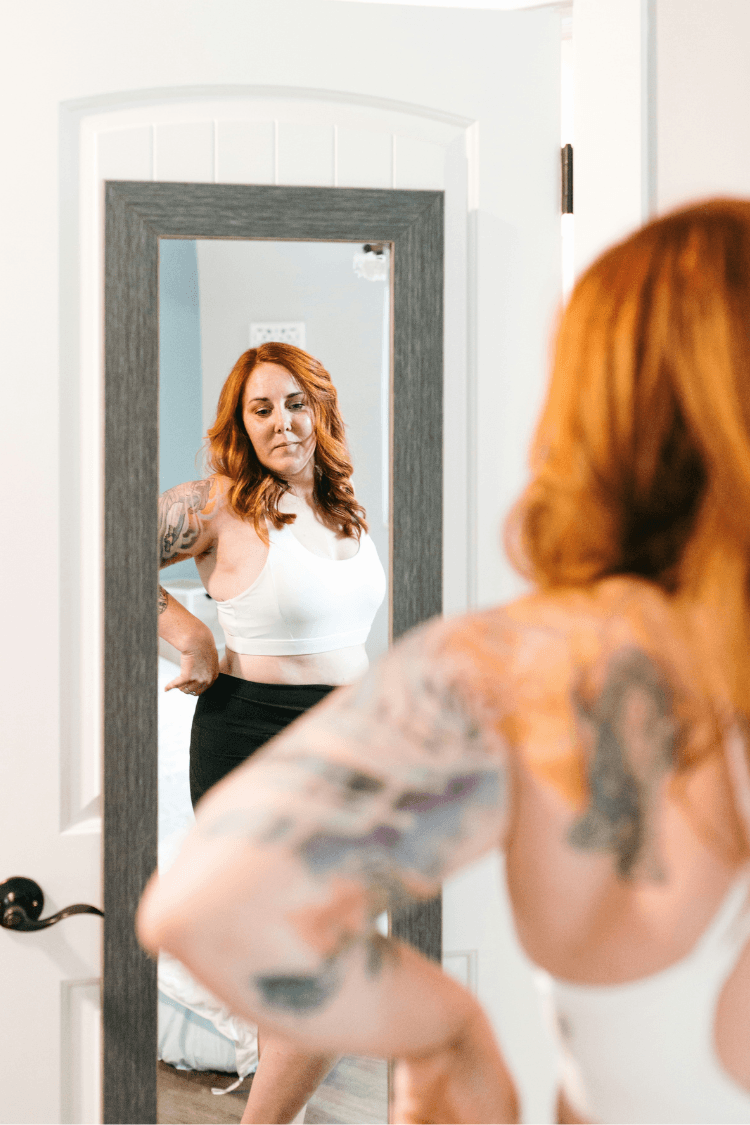 Woman looking at her body in the mirror