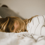 Woman lying face down on bed looking at camera